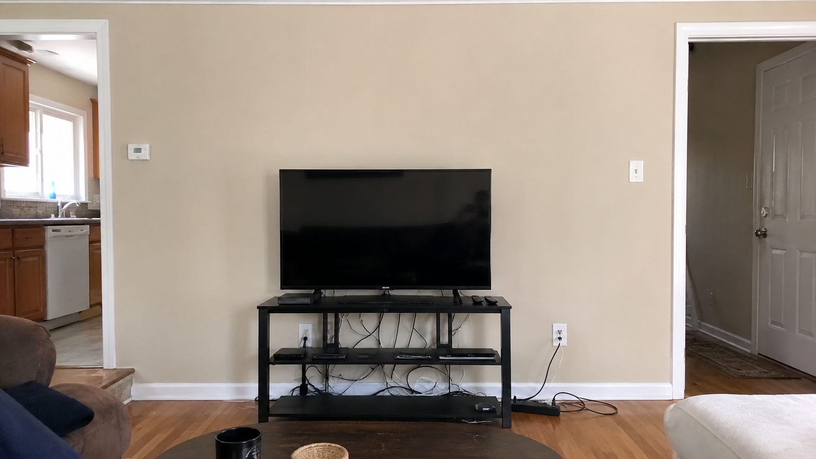 Before: TV on a stand with tangled cables against a bare wall